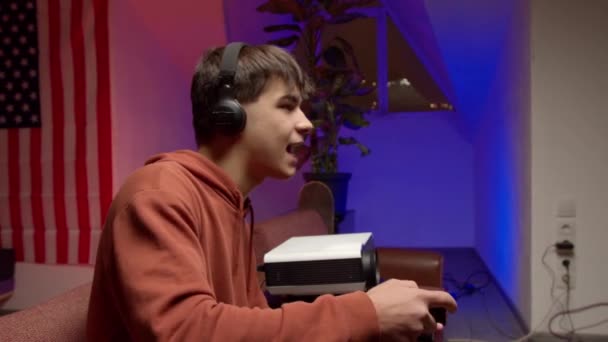 Молодой человек в наушниках играет в видеоигры — стоковое видео