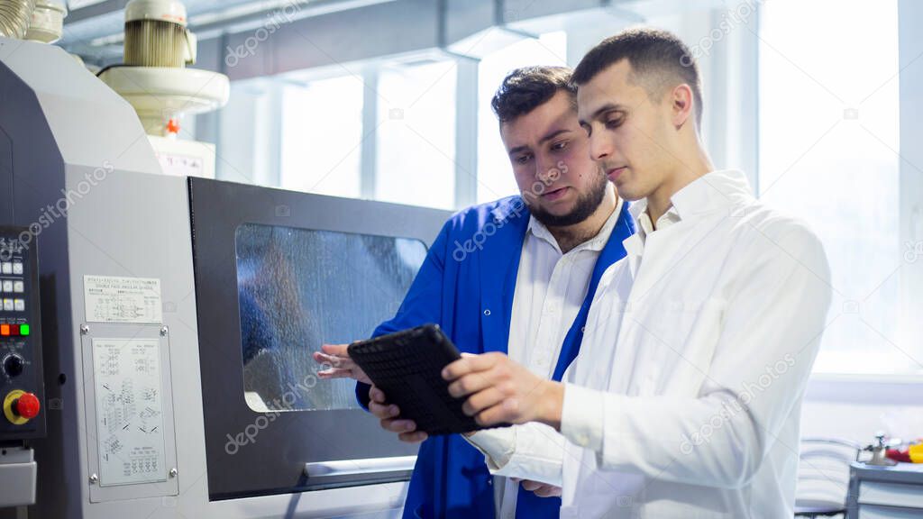 Engineer and technician discussing production process at factory