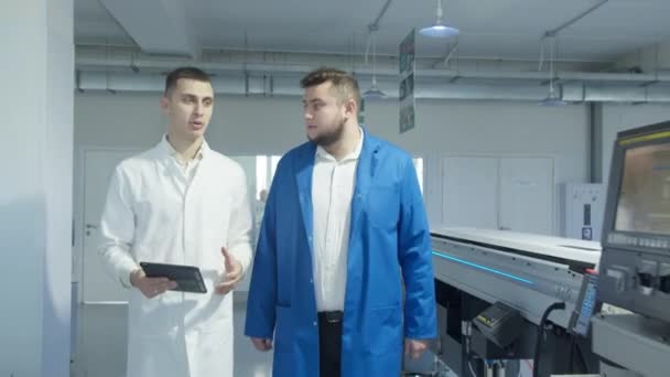 Rekan-rekan yang mendiskusikan pekerjaan alat konveyor di pabrik — Stok Video