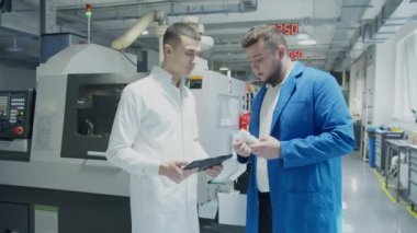 Mühendis ve teknisyen fabrikada üretim sürecini tartışıyor