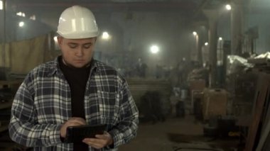 Fabrika atölyesinde tablet kullanan tıknaz erkek çalışan