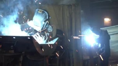 Karanlık atölyede metal kaynak yapan tanınmayan bir çalışan.