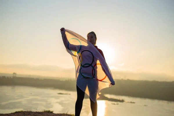 Woman with flag doing martial arts exercises at sunset light