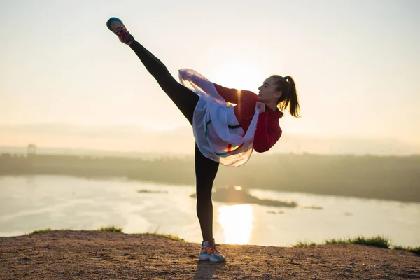 Woman with flag doing martial arts exercises at sunset light