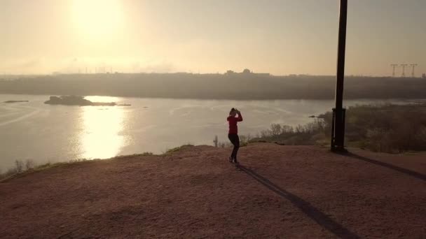 Vrouw die martial arts beoefent aan de rivier bij zonsondergang — Stockvideo