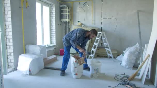 수리하는 동안 양동 이에서 석탄동을 만드는 남성 건축 업자 — 비디오