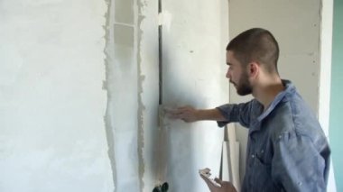 Sakallı müteahhit kablo gövdesine alçı yayıyor.