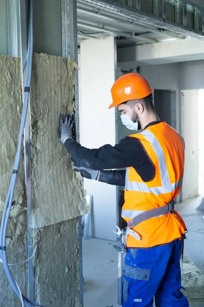 Male builder in mask putting foam into drywall Stock Photo