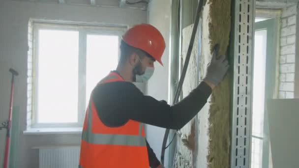 Manlig byggare i mask sätta skum i drywall — Stockvideo