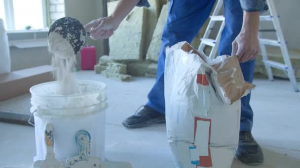 Um trabalhador amassa a mistura em baldes de gesso. — Vídeo de Stock