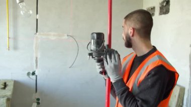 Erkek inşaatçı beton duvarda lazer seviyesi kullanıyor
