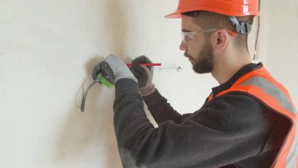 Bearded male contractor measuring and drilling wall — 비디오