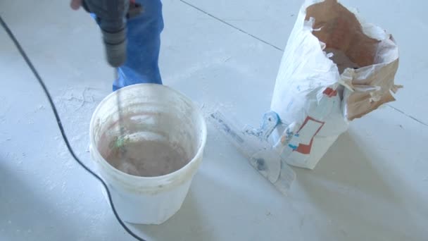 Male builder mixing stucco with drill in bucket — Stock Video