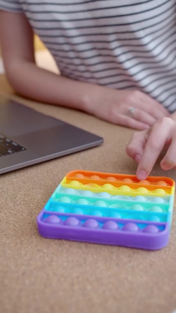 Женщина играет с цветной силиконовой антистрессовой игрушкой. Вертикальное видео — стоковое видео