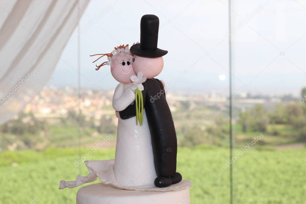 Munecos de torta de matrimonio en primer plano, con fondo del campo en la ciudad de Arequipa en Peru. Ideal para promocionar cursos de pasteleria o decoraciones de bodas.