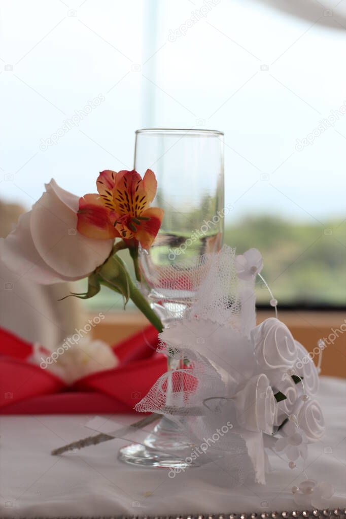 Primer plano de copa de cristal decorada con flores y cintas para que la novia la use en el brindis de los recien casados. Imagen ideal para promocionar decoraciones y menaje.