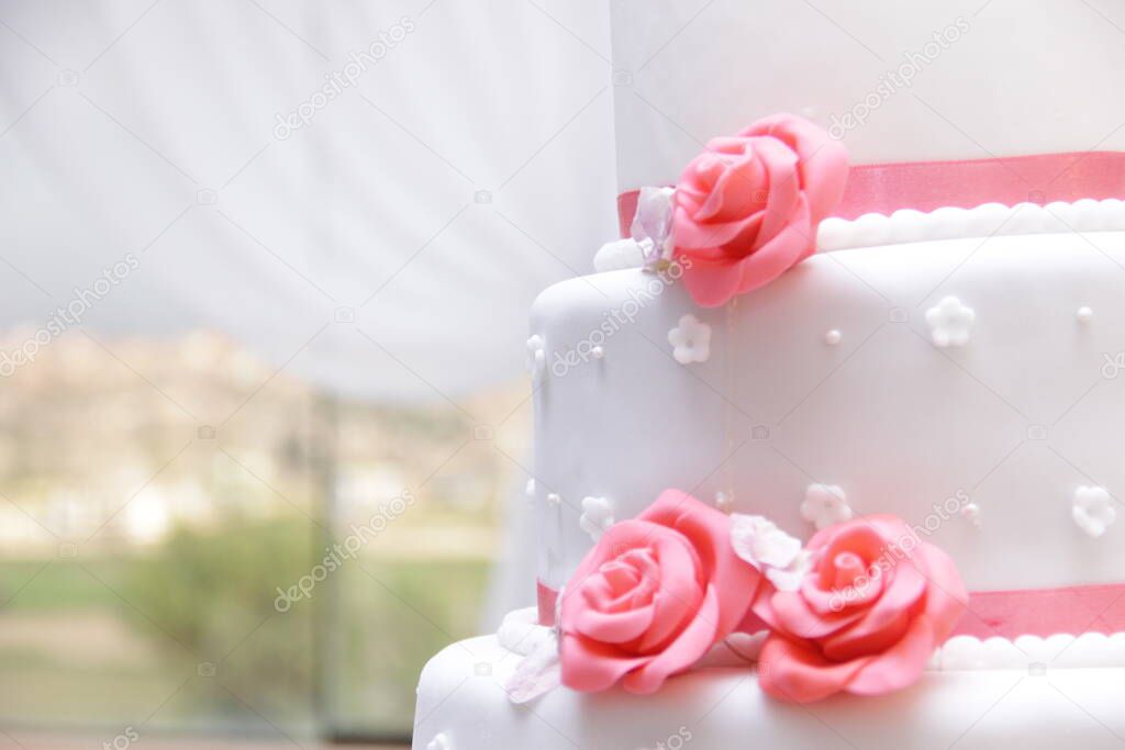 Detalle en primer plano de torta de matrimonio color blanco con decoracion de rosas comestibles elaboradas en masa elastica. Imagen ideal para promocionar pasteleria.