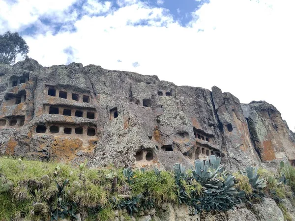 Ventanillas de Otuzco, bulutlu bir gökyüzü arka planına sahip; bunlar Cajamarca kenti yakınlarındaki yerleşim alanlarında ikamet eden antik mezarlardır - Peru.