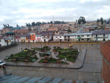 Vista en pleno amanecer de la plaza del pueblo de Santo Tomas en la provincia de Chumbivilcas - Cusco, con el cielo despejandose de las nubes, de la misma forma se observa casas rusticas.
