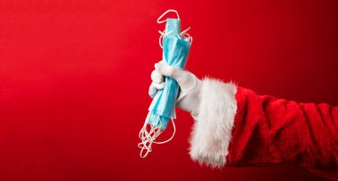 Noel Baba ellerinde koronavirüs cerrahi yüz maskesi tutuyor. Kapalı Noel