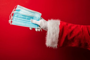 Noel Baba ellerinde koronavirüs cerrahi yüz maskesi tutuyor. Kapalı Noel