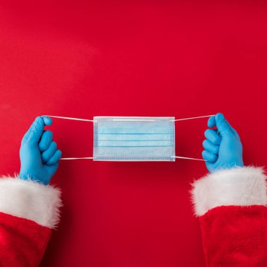 Noel Baba ellerinde koronavirüs cerrahi yüz maskesi tutuyor. Kapalı Noel