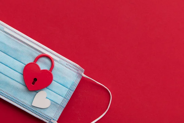 Amor en Lockdown. Candado de San Valentín en forma de corazón rojo sobre una máscara de coronavirus — Foto de Stock