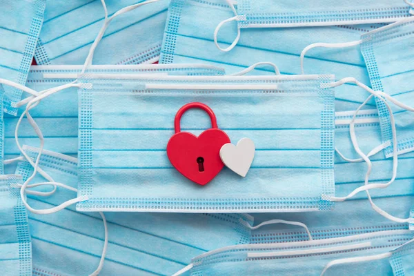 Candado en forma de corazón sobre una mascarilla protectora. Concepto de día de San Valentín covid — Foto de Stock