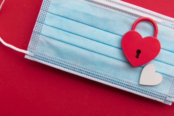 Liefde in Lockdown. Rood hartvormige valentijn hangslot op een coronavirus masker — Stockfoto