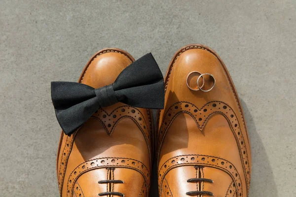 Groom wedding day background. Leather shoes bow tie and rings