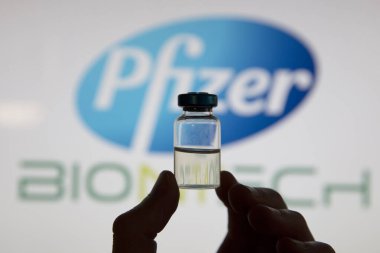 OXFORD, İngiltere - Şubat 2020: Pfizer logosunun önünde bir covid aşı şişesi