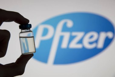 OXFORD, İngiltere - Şubat 2020: Pfizer logosunun önünde bir covid aşı şişesi