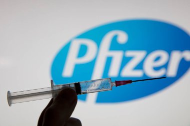 OXFORD, İngiltere - Şubat 2020: Pfizer logosu önünde bir covid aşı şırıngası