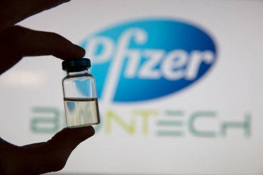 OXFORD, İngiltere - Şubat 2020: Pfizer logosunun önünde bir covid aşı şişesi