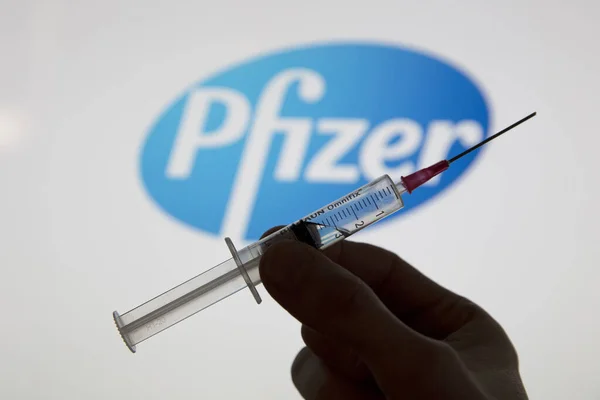 OXFORD, İngiltere - Şubat 2020: Pfizer logosu önünde bir covid aşı şırıngası — Stok fotoğraf