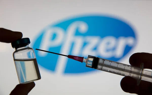 OXFORD, İngiltere - Şubat 2020: Pfizer logosu önünde bir covid aşı şırıngası — Stok fotoğraf