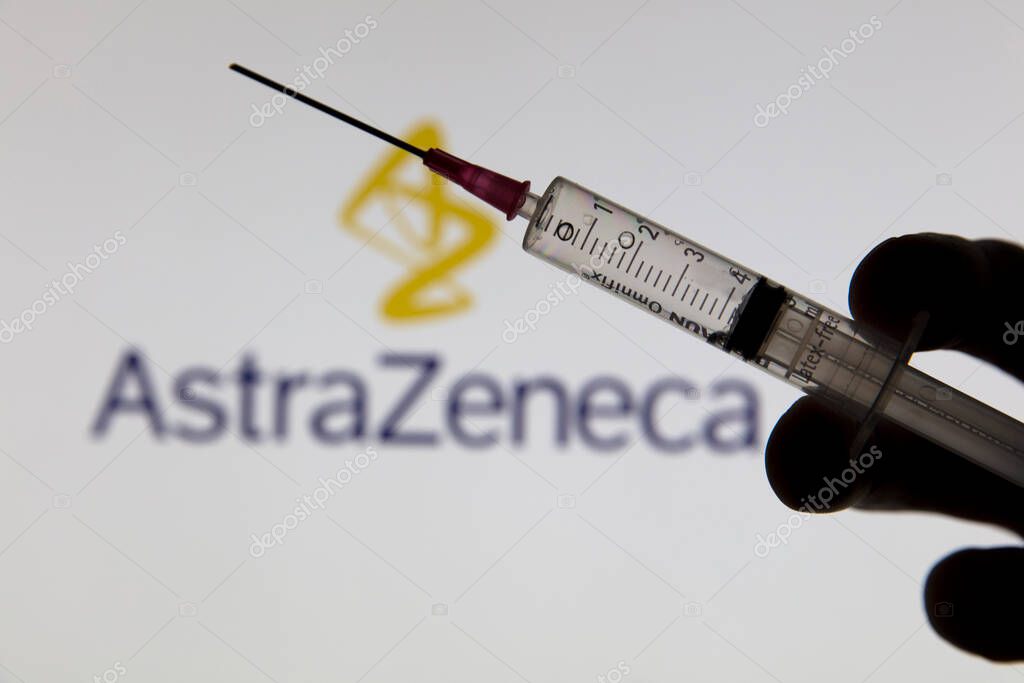OXFORD, UK - February 2020: Covid vaccine syringe in front of Astrazeneca logo.