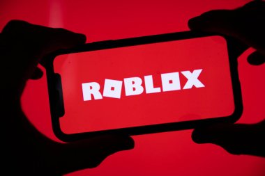 LONDON, UK - March 2021: Person holding a smartphone with Roblox game logo clipart