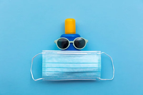 Coronavirus vacances d'été fond. Crème solaire avec lunettes de soleil et masque facial — Photo