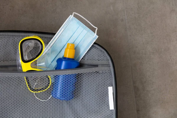Захисна хірургічна маска, сонячний крем та маска для підводного плавання у валізі — стокове фото