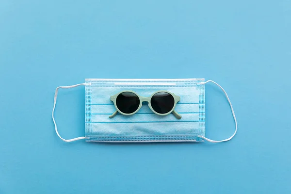 Een zonnebril op een beschermend gezichtsmasker. Zomervakantie concept — Stockfoto