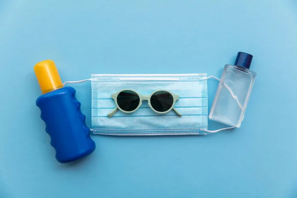 Sonnencreme und Desinfektionsflasche auf einer medizinischen Schutzmaske. Lebendiger Sommer — Stockfoto