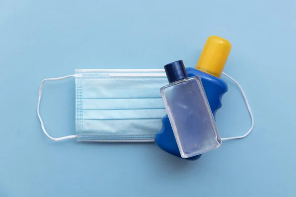 Zonnecrème en reinigingsmiddel fles op een beschermend medisch gezichtsmasker. Gezellige zomer — Stockfoto