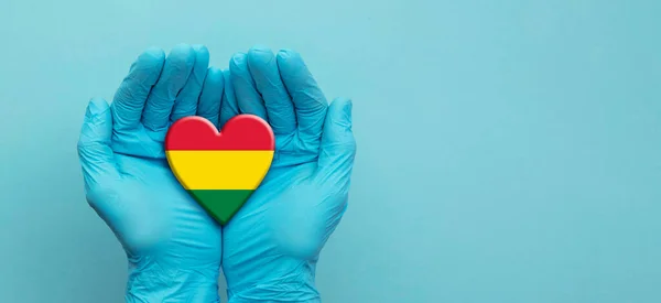 Lékařské ruce v chirurgických rukavicích držící bolívijské srdce — Stock fotografie