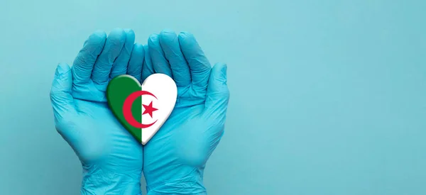 Médicos con guantes quirúrgicos sosteniendo la bandera de Argelia corazón — Foto de Stock