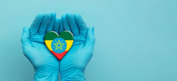 Médicos con las manos con guantes quirúrgicos sosteniendo Etiopía bandera corazón — Foto de Stock