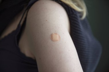 Aşı olduktan sonra kolunda alçı olan beyaz bir kadın.