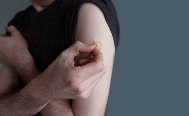 Aşı olduktan sonra kolunda alçı olan beyaz bir adam.