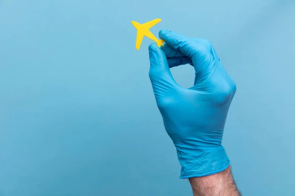 En person som bär en medicinsk kirurgisk handske som håller i ett gult flygplan — Stockfoto