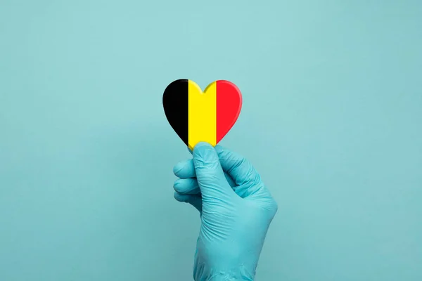 戴着印有比利时国旗心脏的保护性外科手套的手 — 图库照片